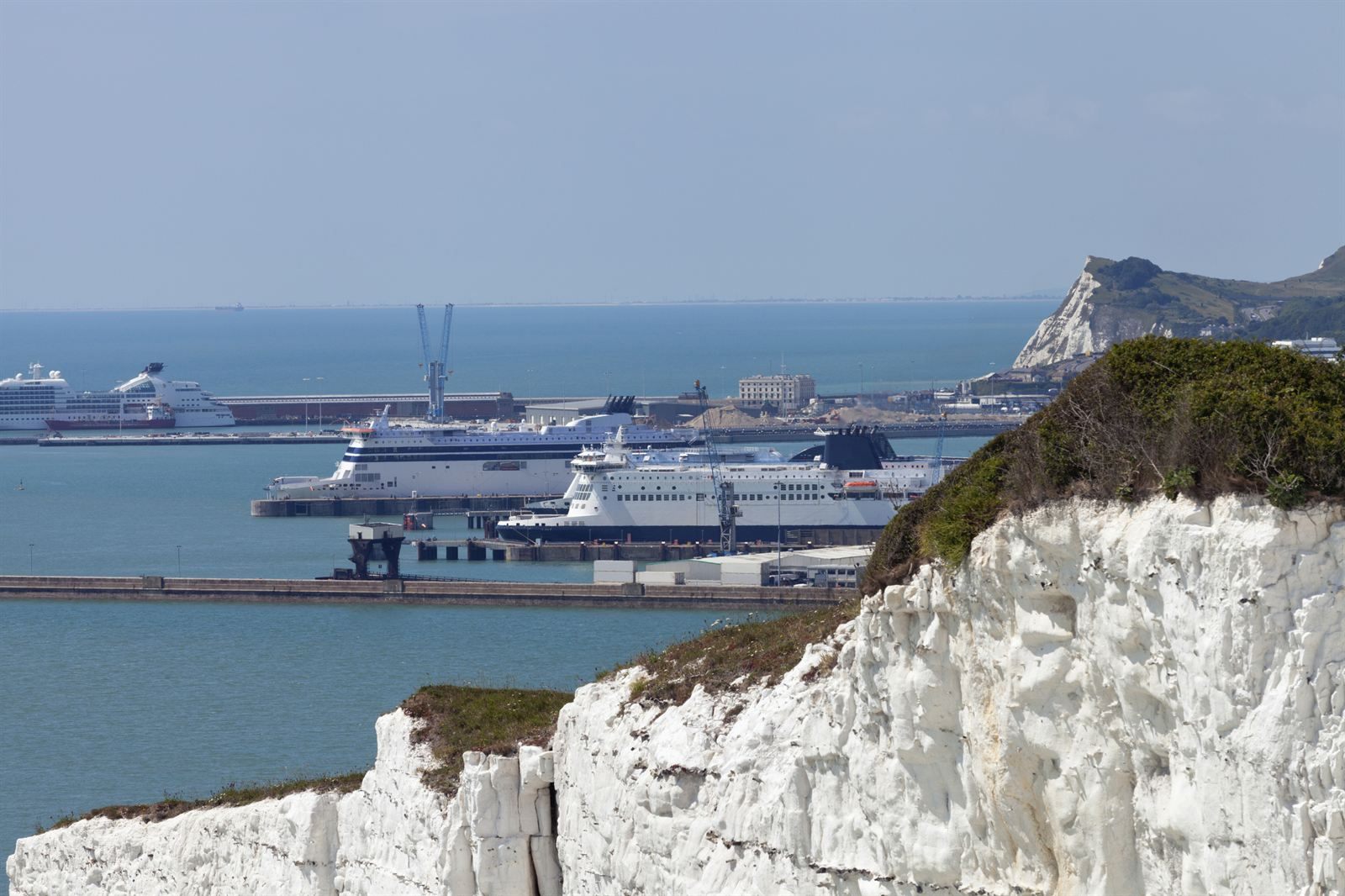 White chalk cliffs above the port of Dover, with ferries and a cruise ship berthed in the harbor