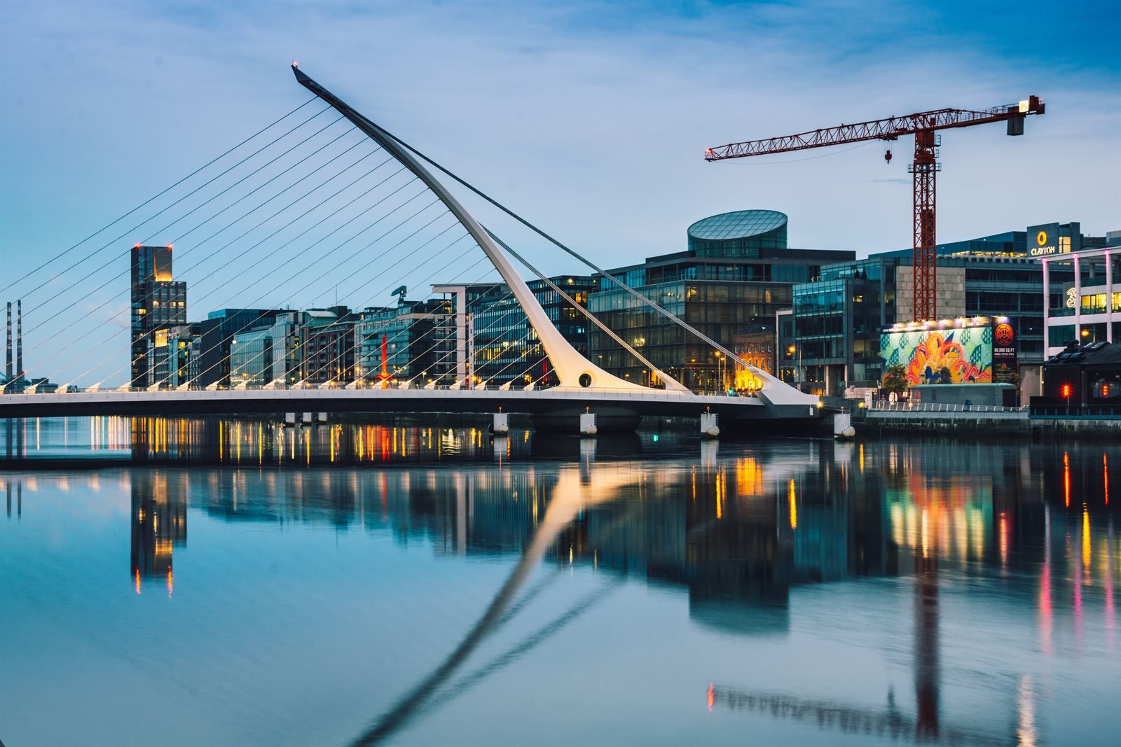 The harp-shaped Samuel Beckett Bridge over the River Liffey in Dublin at dusk, reflected in the water