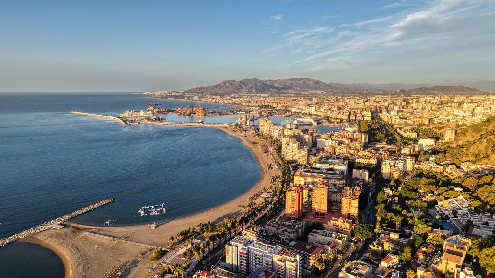 Aerial view of Málaga&rsquo;s beach and harbor, with the city and mountains behind