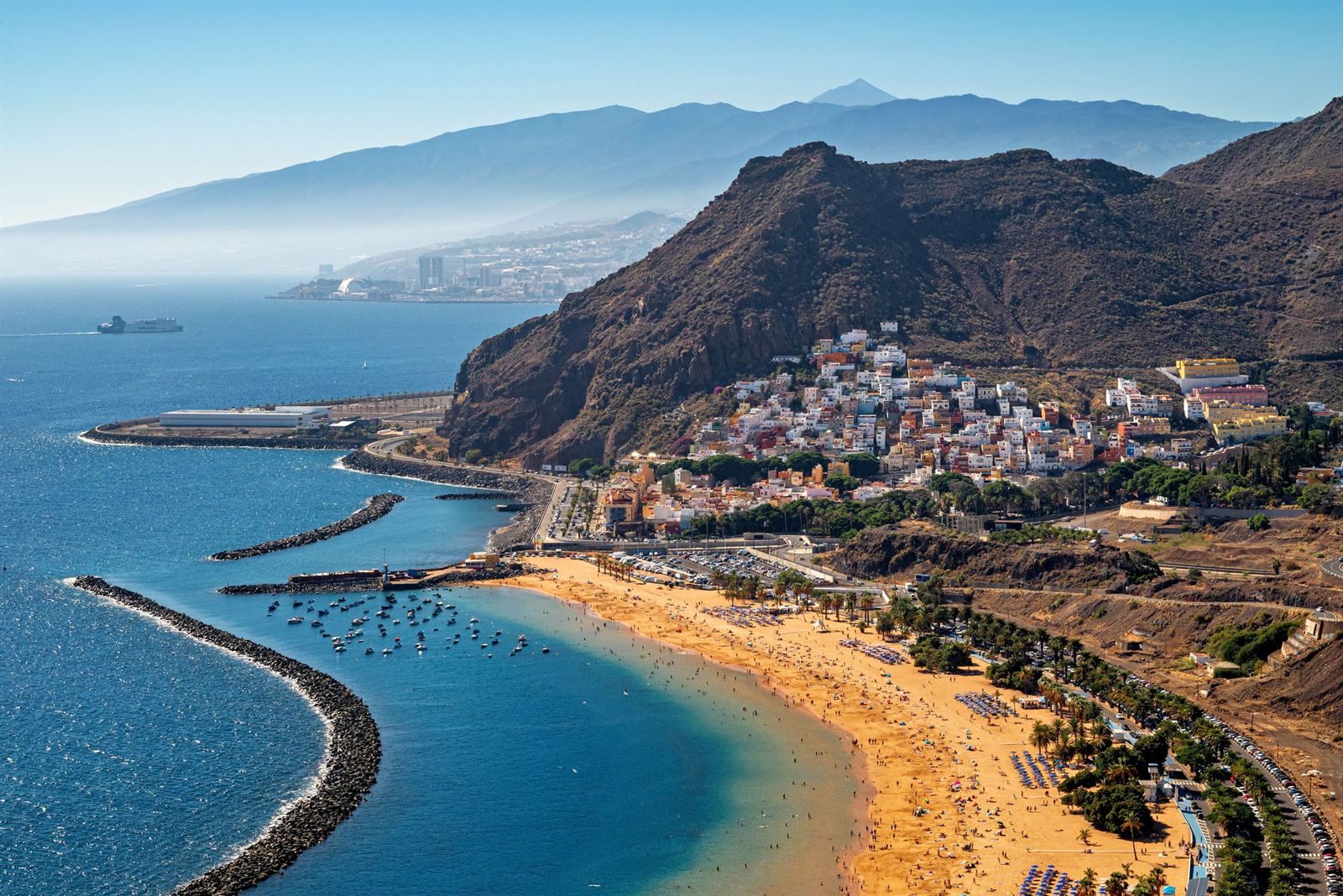 Golden sand beach and breakwaters of Las Teresitas beside the village of San Andrés on Tenerife, with Mount Teide on the horizon